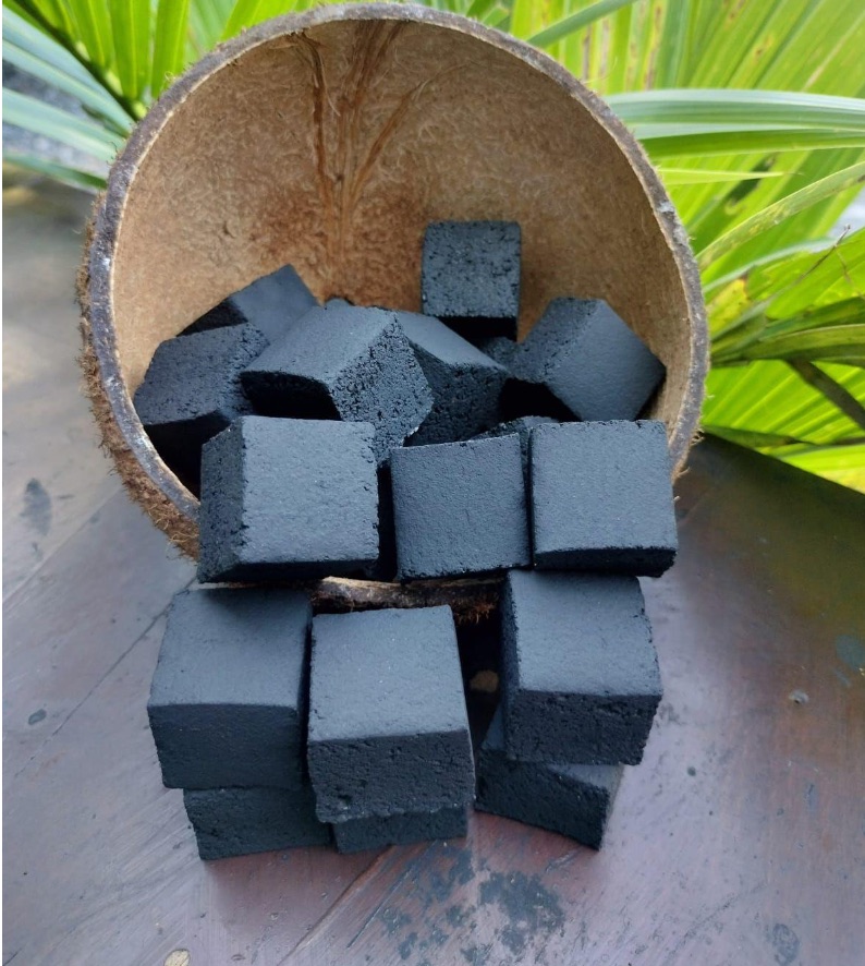 Coconut shell charcoal cubes arranged beside a coconut shell